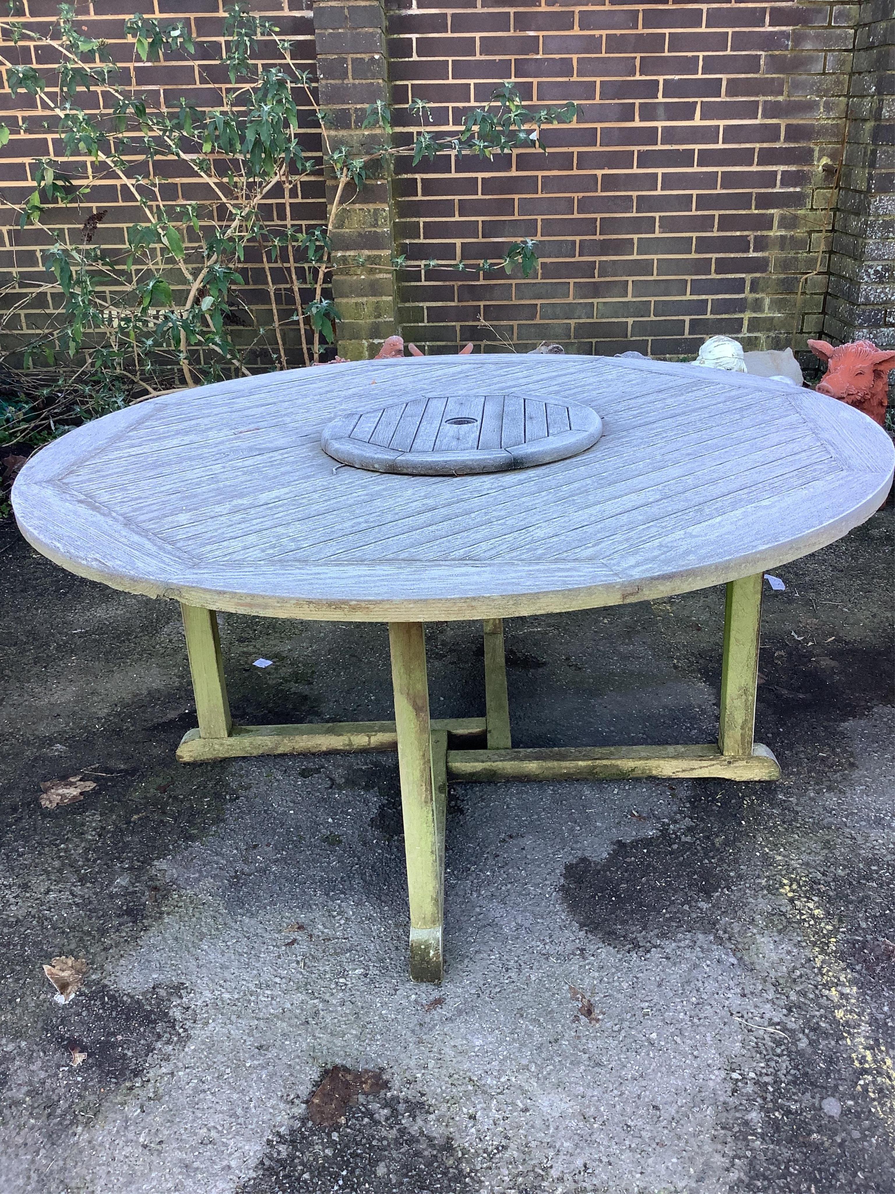 A teak garden bench and a teak circular table, table diameter 148cm, height 70cm. Condition - fair